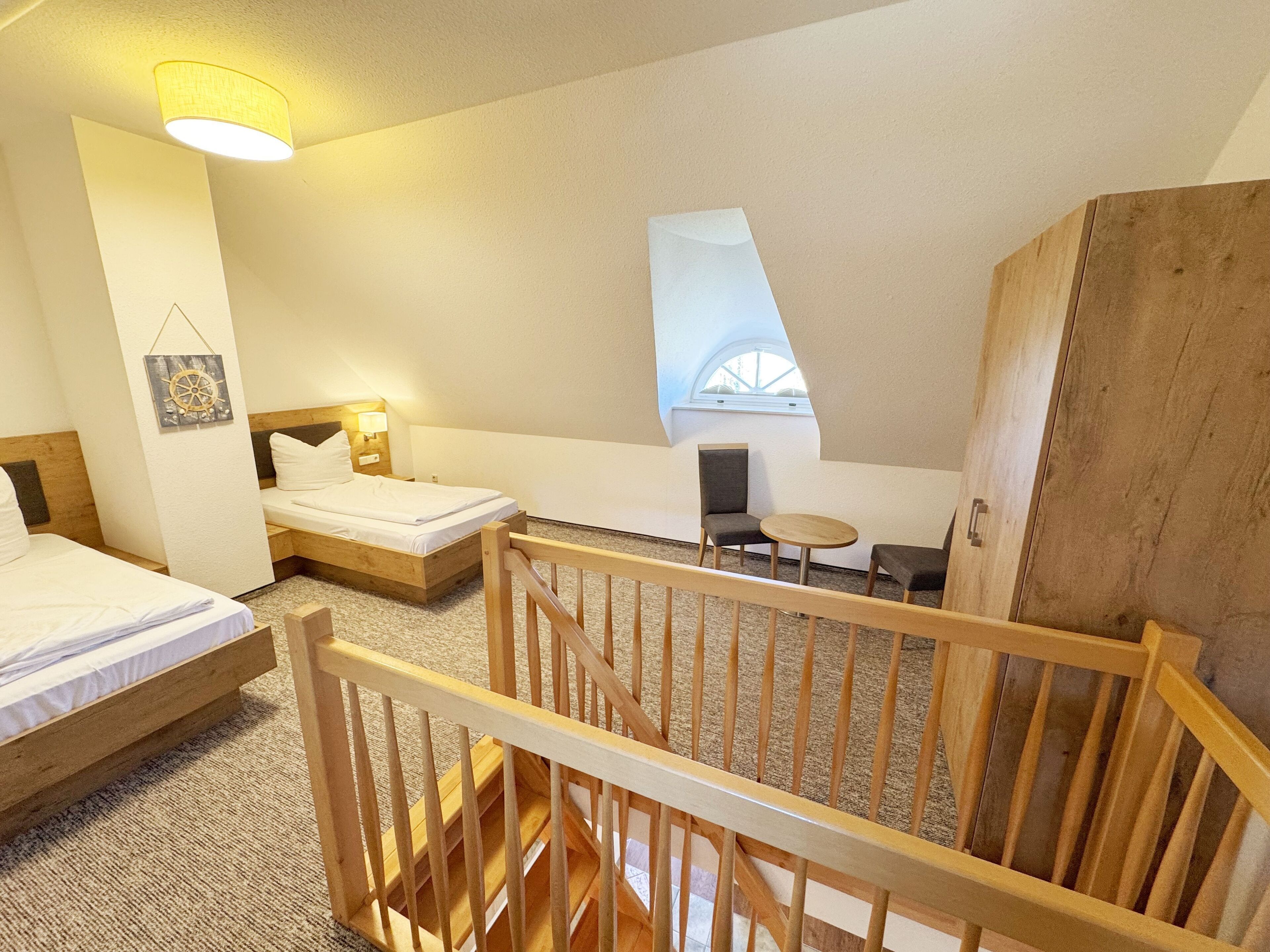 Een slaapkamer met twee bedden, een klein tafeltje en een raam.