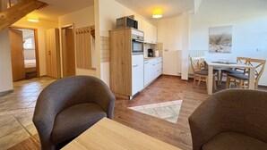 Una cucina moderna con mobili bianchi e forno integrato. C'è una zona pranzo con tavolo e sedie, e una scala che conduce a un'altra stanza.