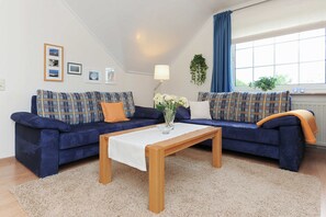 A living room with two blue sofas, a wooden coffee table, and a beige carpet.