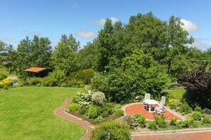 A well-maintained garden with a patio area, a pathway, and a building with a red roof.