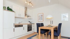 Una cocina moderna con armarios blancos, una mesa de comedor de madera y sillas azules.