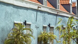 Een gebouw met een blauwe gevel, rode pannendaken en grote potplanten ervoor.