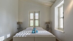 Een slaapkamer met een groot bed, twee nachtkastjes en een raam met zonwering.