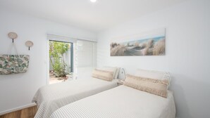 A bedroom with two beds, a view of the outdoors, and a painting on the wall. - Pippis on Pacific - fantastic two-level townhouse located opposite Yamba's beautiful Pippi Beach (Yamba)