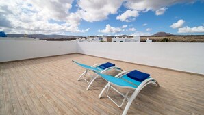 Une terrasse sur le toit, dotée d’un plancher en bois et de trois chaises longues.