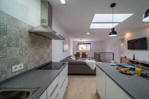 Eine moderne Küche mit einer zentralen Kochinsel, einem Essbereich mit einer Couch und einem an der Wand montierten Fernseher.