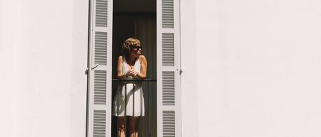 A person standing in a window with white shutters.