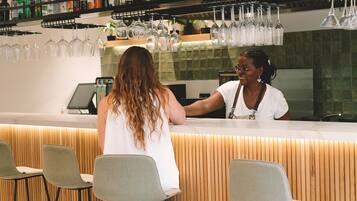 A bar area with a counter, stools, and a variety of bottles and glasses.