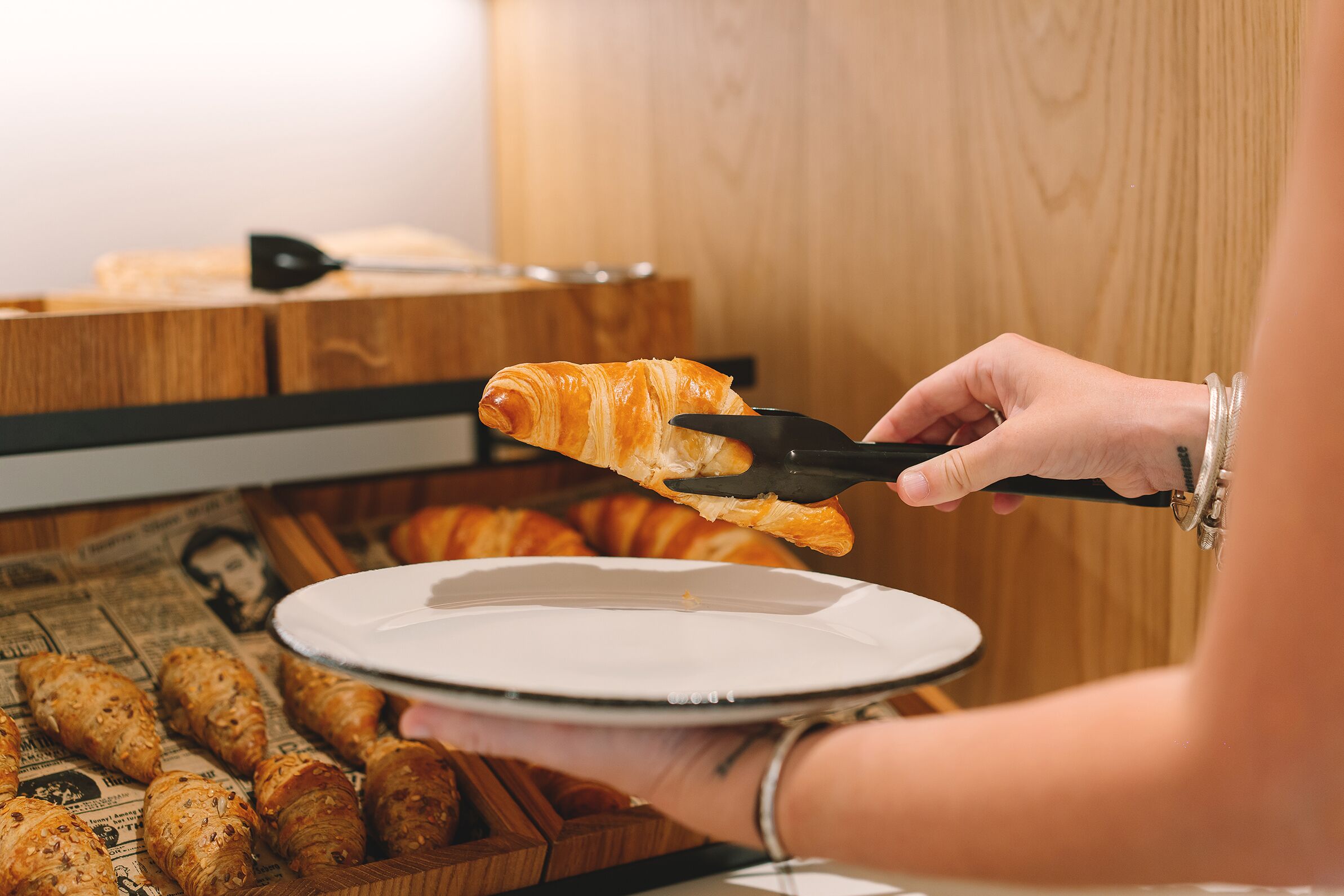 Une personne tenant une assiette avec un croissant et un couteau.
