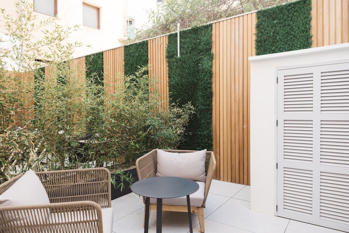 A patio area with wicker furniture, a round table, and a green vertical garden wall.