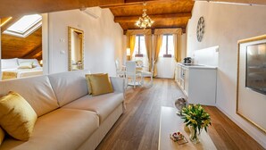A cozy living room with a sofa, a dining table, and a kitchen area. - Laguna D 'oro Luxury Apartments - Exclusive Sky Suite (Venezia)