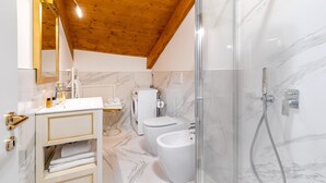 A modern bathroom with a wooden ceiling, marble flooring, a glass-enclosed shower, a white sink, and a toilet. - Laguna D 'oro Luxury Apartments - Exclusive Sky Suite (Venezia)