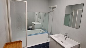 Une salle de bain avec une baignoire, un lavabo, un miroir et des toilettes.
