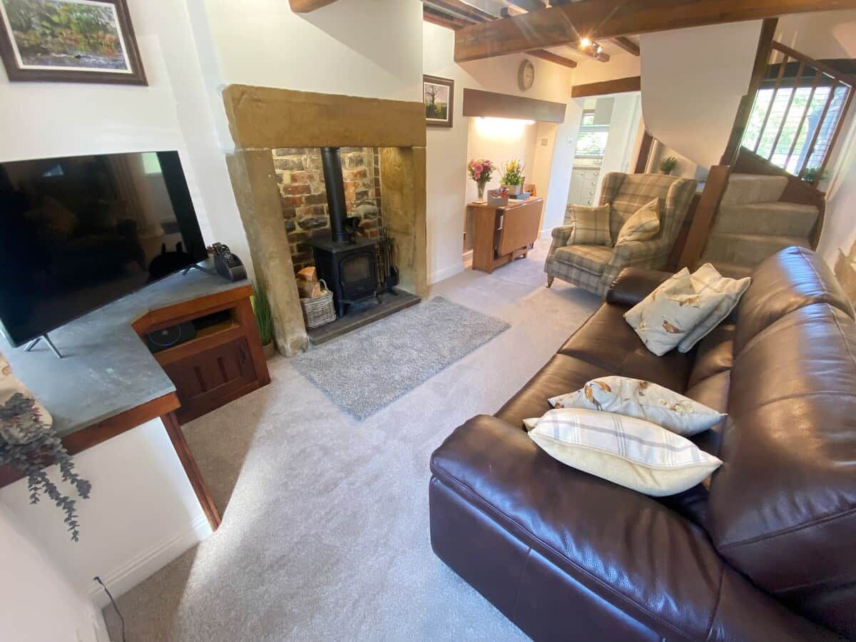 A cozy living room with a fireplace, leather sofa, and a flat-screen TV.
