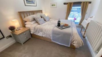 Ein ordentlich eingerichtetes Schlafzimmer mit einem Bett, einem Nachttisch, einer Lampe und einem Fenster mit Vorhängen.