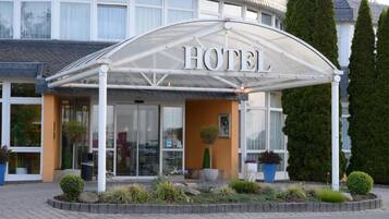 A hotel with a covered entrance, large windows, and a landscaped garden area.