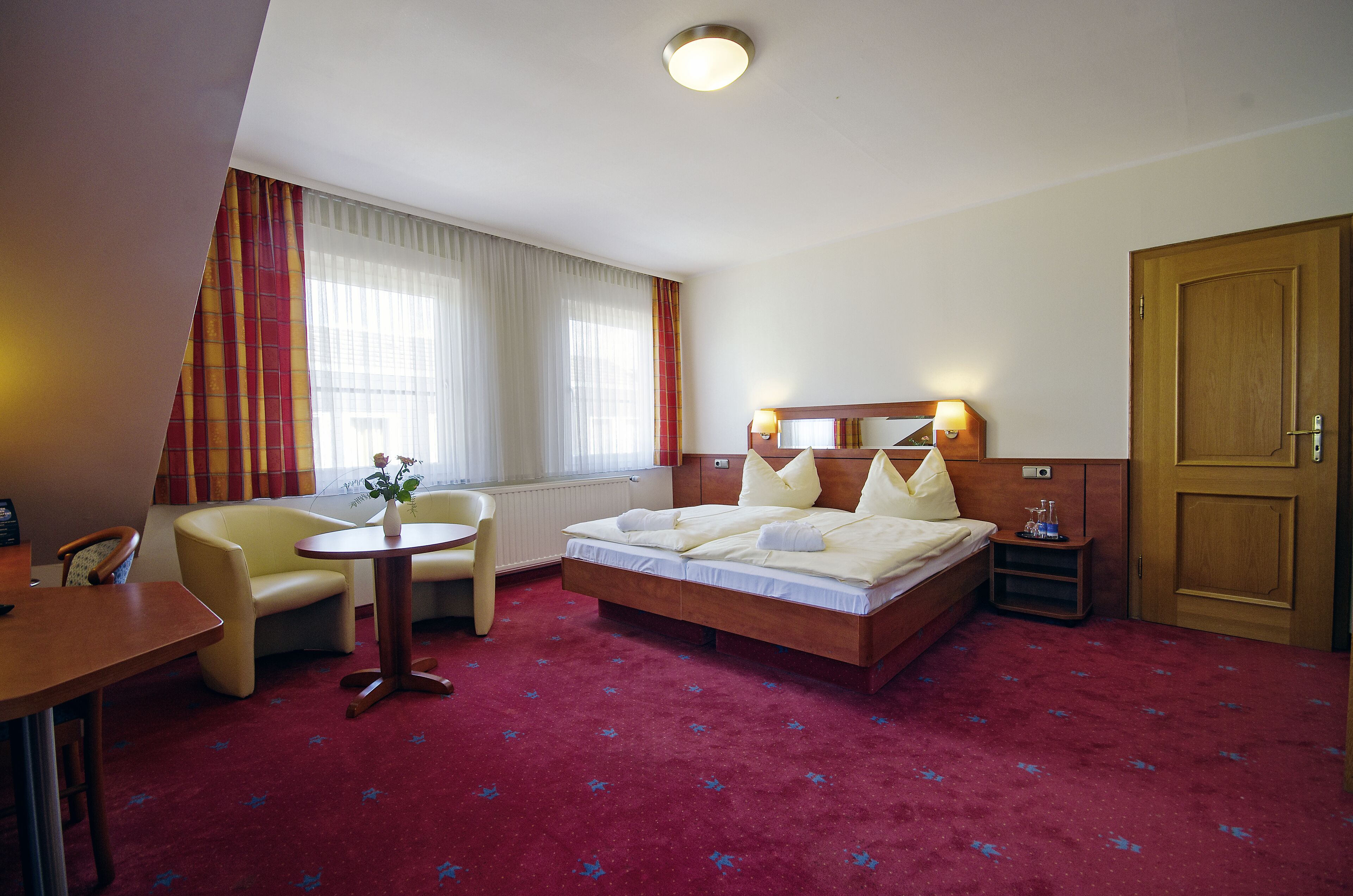 Ein Hotelzimmer mit einem Bett, einem Schreibtisch, einem Stuhl und einem kleinen Tisch mit einer Vase.
