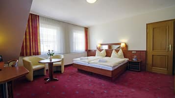 Ein Hotelzimmer mit einem Bett, einem Schreibtisch, einem Stuhl und einem kleinen Tisch mit einer Vase.