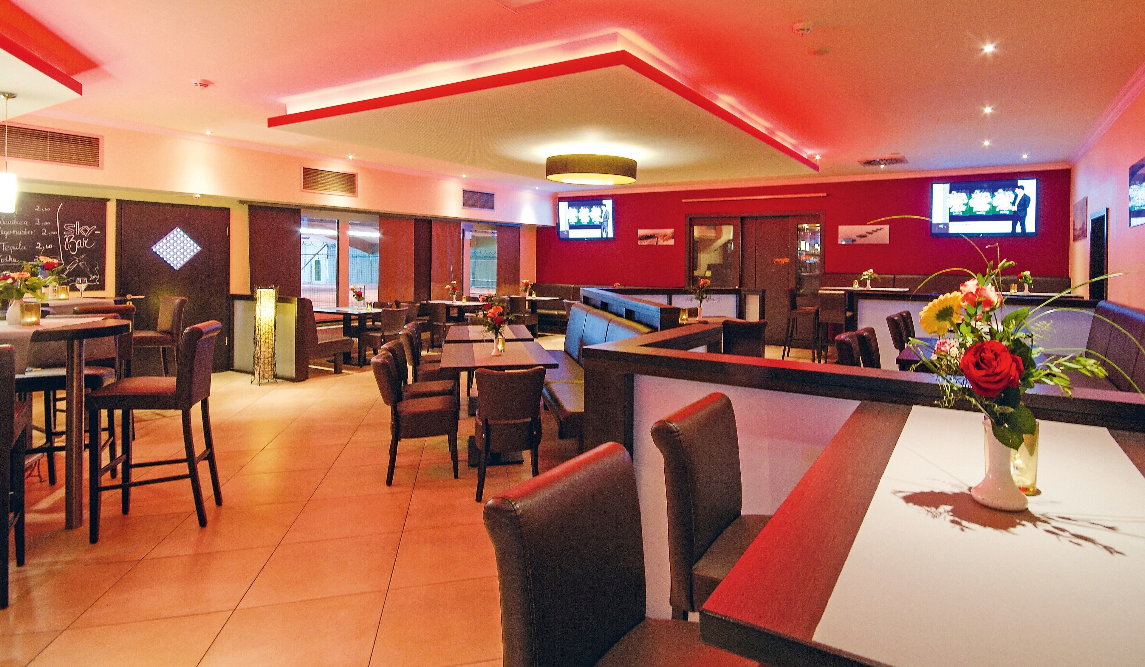 Ein Restaurant mit Sitzgelegenheiten in Form von Boxen und Tischen, einer Bar und einem Fernsehbildschirm.