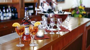 A bar area with a bottle of Aperitivo, two glasses of a dark amber beverage, and a fruit garnish. - AVALON Hotelpark Königshof (Königslutter am Elm)