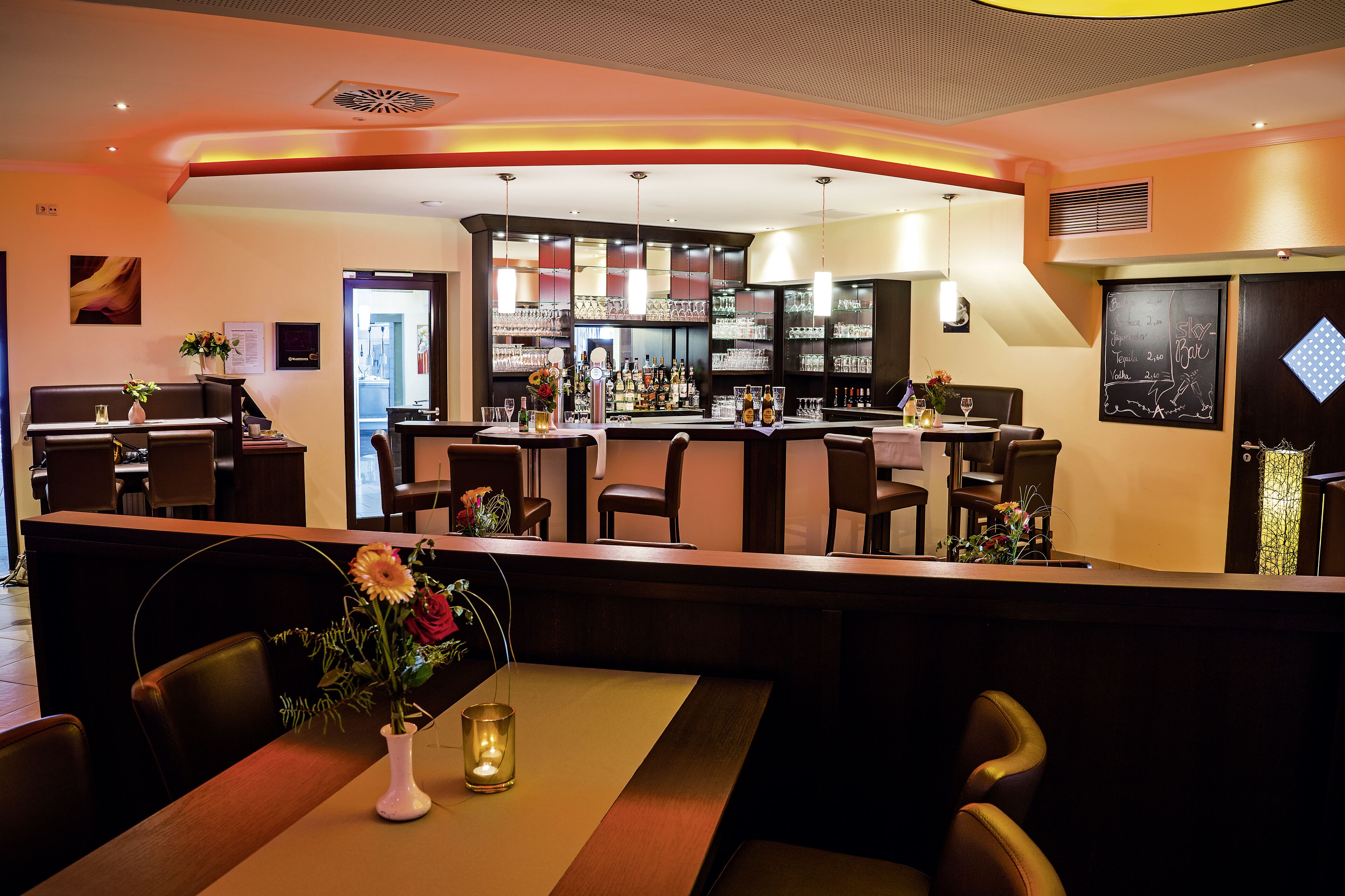 A bar area with a counter, seating, and a bar stocked with bottles and glasses.