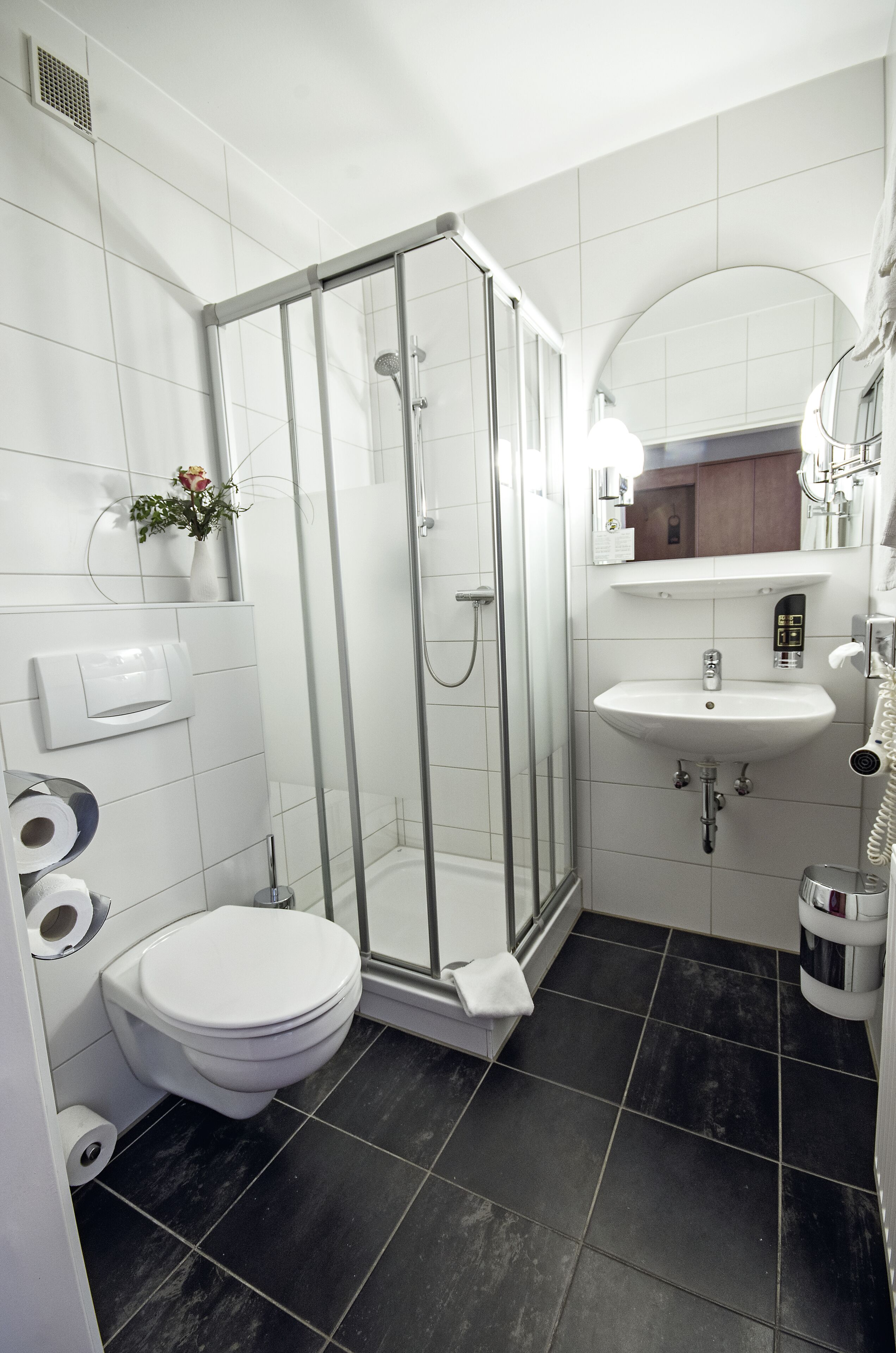 Ein modernes Badezimmer mit einer Duschkabine, einem weißen Waschbecken und einer Toilette.