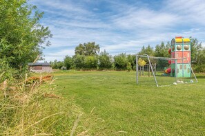 A grassy field with a colorful play structure and a soccer goal.