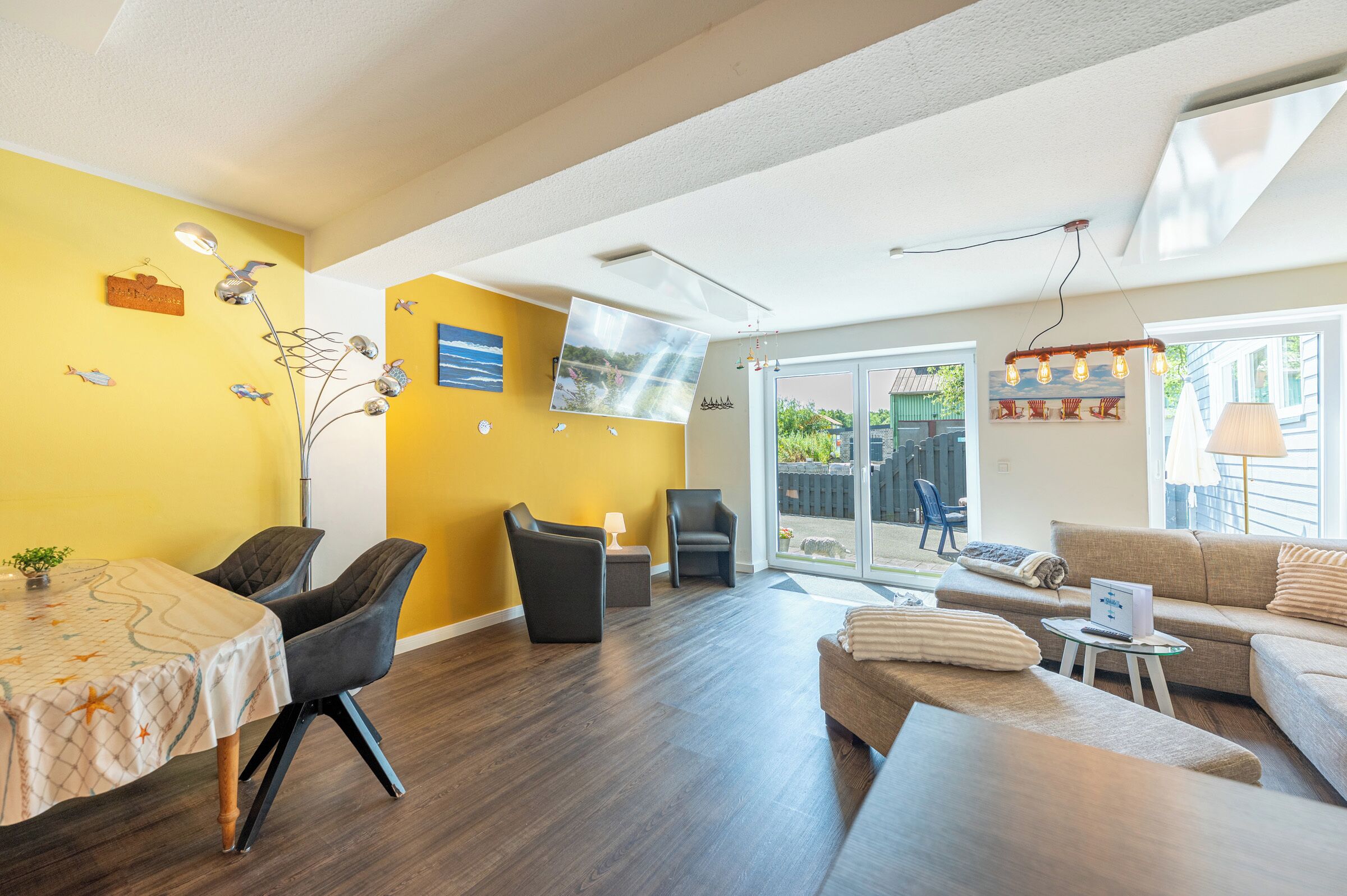 A modern living room with a yellow accent wall, a dining area with a table and chairs, and a seating area with a sofa and armchairs.