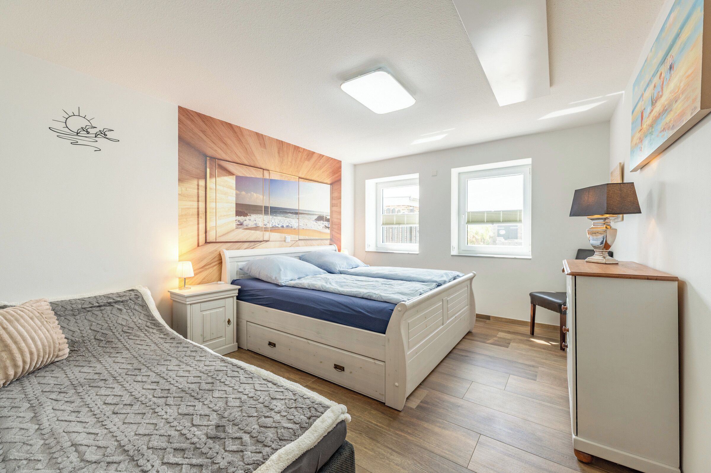 Ein Schlafzimmer mit Bett, Nachttisch, Lampe und einem Bild an der Wand.
