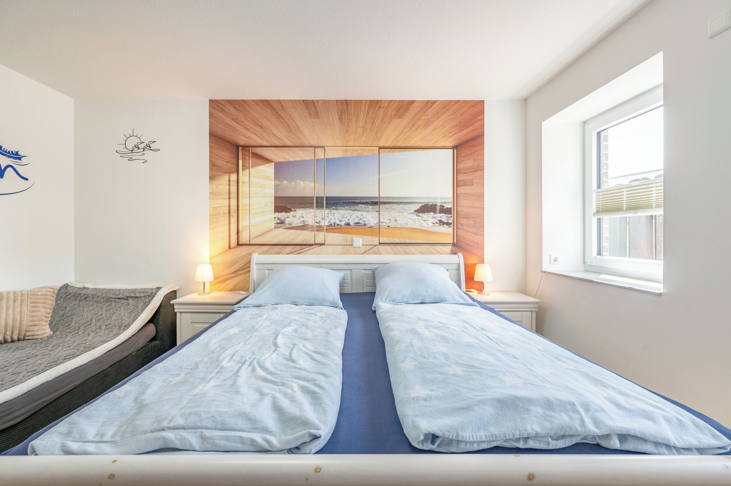 A room with a bed, a sofa, and a large window.