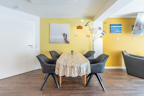 A dining area with a table set for four, surrounded by chairs, in a room with yellow walls and a white ceiling. - "Landliebe" Vacation Rental in Husum-Schauendahl for up to 4 people (Husum-Schauendahl)