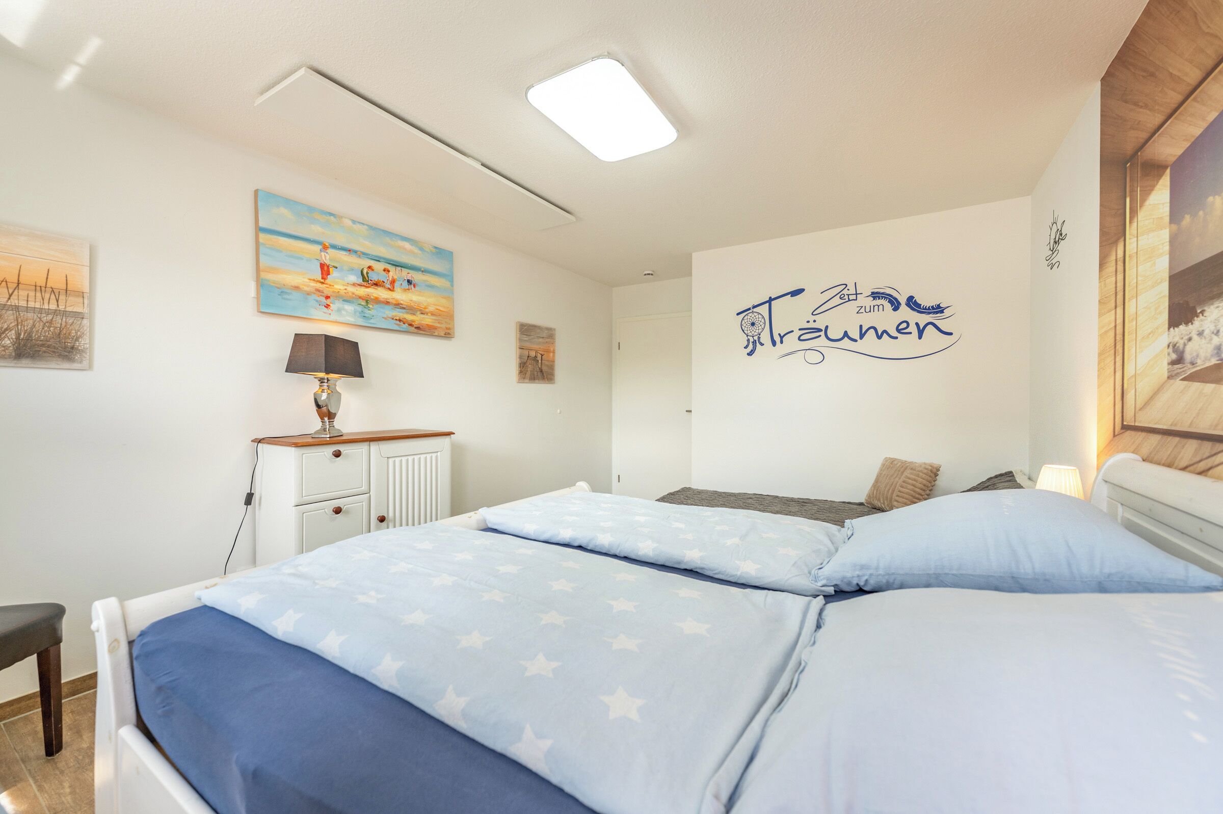 Une chambre à coucher avec un lit, un bureau et un mur orné d’un tableau et d’une affiche.