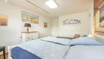 Une chambre à coucher avec un lit, un bureau et un mur orné d’un tableau et d’une affiche.