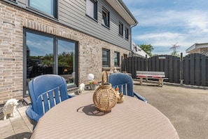 A patio with a round table, two blue chairs, a wicker vase, and a wooden fence. - "Landliebe" Vacation Rental in Husum-Schauendahl for up to 4 people (Husum-Schauendahl)