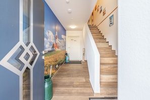 A modern interior with a wooden staircase, a mural of a lighthouse, and a door labeled 'Moin'. - "Landliebe" Vacation Rental in Husum-Schauendahl for up to 4 people (Husum-Schauendahl)