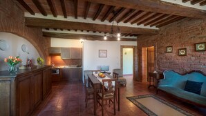 Une cuisine rustique avec des meubles en bois, une table à manger avec des chaises, un canapé et un lustre.