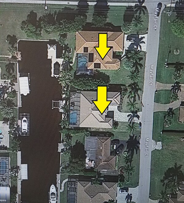An aerial view of a residential area with two houses marked by yellow arrows, indicating a specific location. - Two homes that exude luxury and comfort, Heated Pools - Villa Blue Pavilion- Roelens Vacations (Cape Coral)