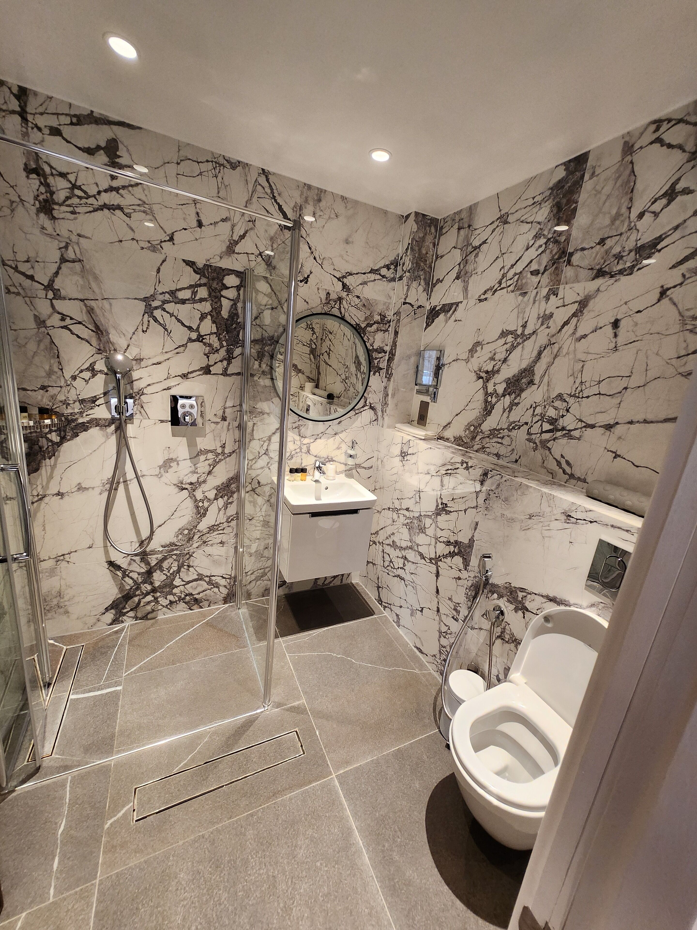 Een moderne badkamer met een douchecabine van glas, een wastafel en een toilet.