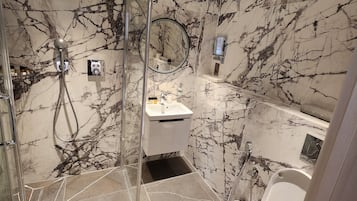 Een moderne badkamer met een douchecabine van glas, een wastafel en een toilet.