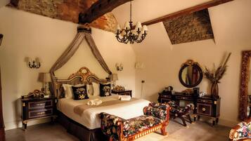 Un dormitorio con cama con dosel, candelabro, espejo grande y sofá floral.