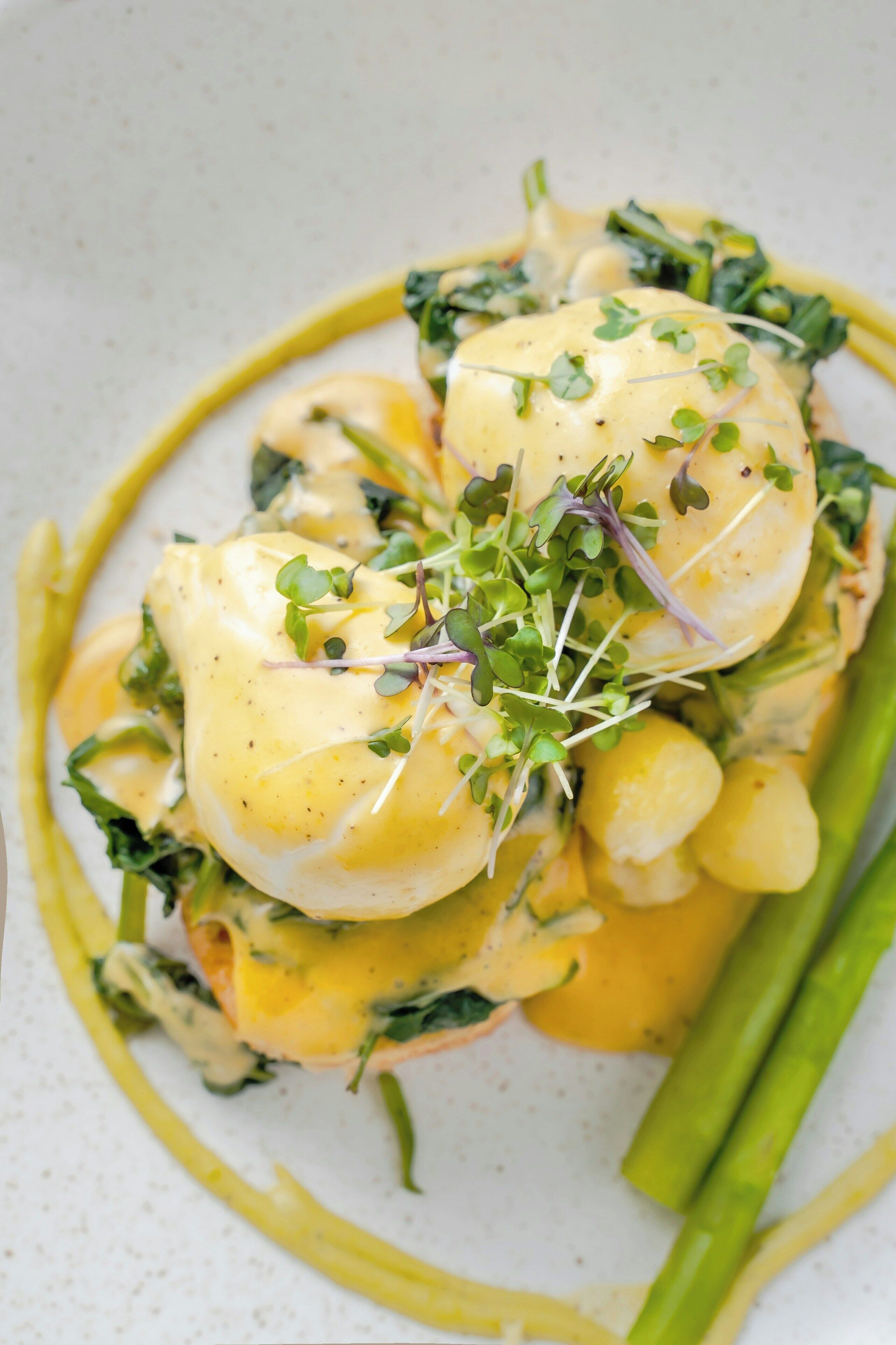 A dish with poached eggs, greens, and asparagus on a plate.