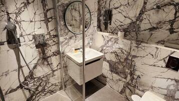Un baño moderno con cabina de ducha de vidrio, un lavamanos blanco y un inodoro.