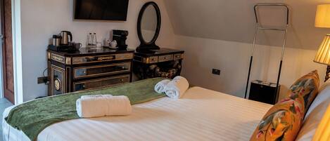 A hotel room with a bed, a flat-screen TV, a dresser, a mirror, a lamp, and a window.