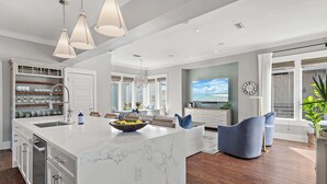 A modern kitchen with a large island, built-in shelves, and pendant lighting. - New Reno!- Steps to Beach- Elevator- Golf Cart (Santa Rosa Beach)