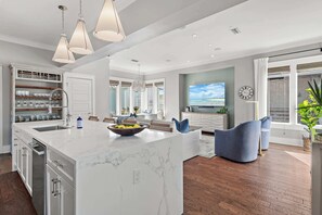A modern kitchen with a large island, built-in shelves, and pendant lighting.