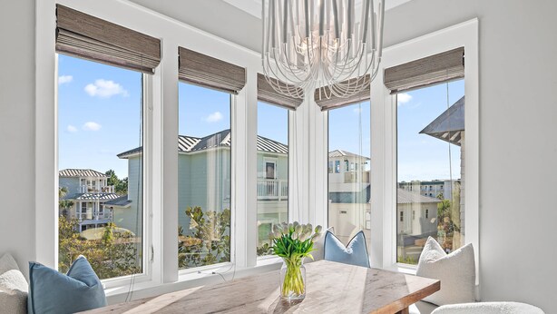 A dining area with a wooden table, white chairs, and a vase of flowers. - New Reno!- Steps to Beach- Elevator- Golf Cart (Santa Rosa Beach)