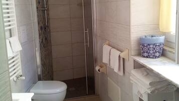 Une petite salle de bain avec des toilettes, une douche et un lavabo.