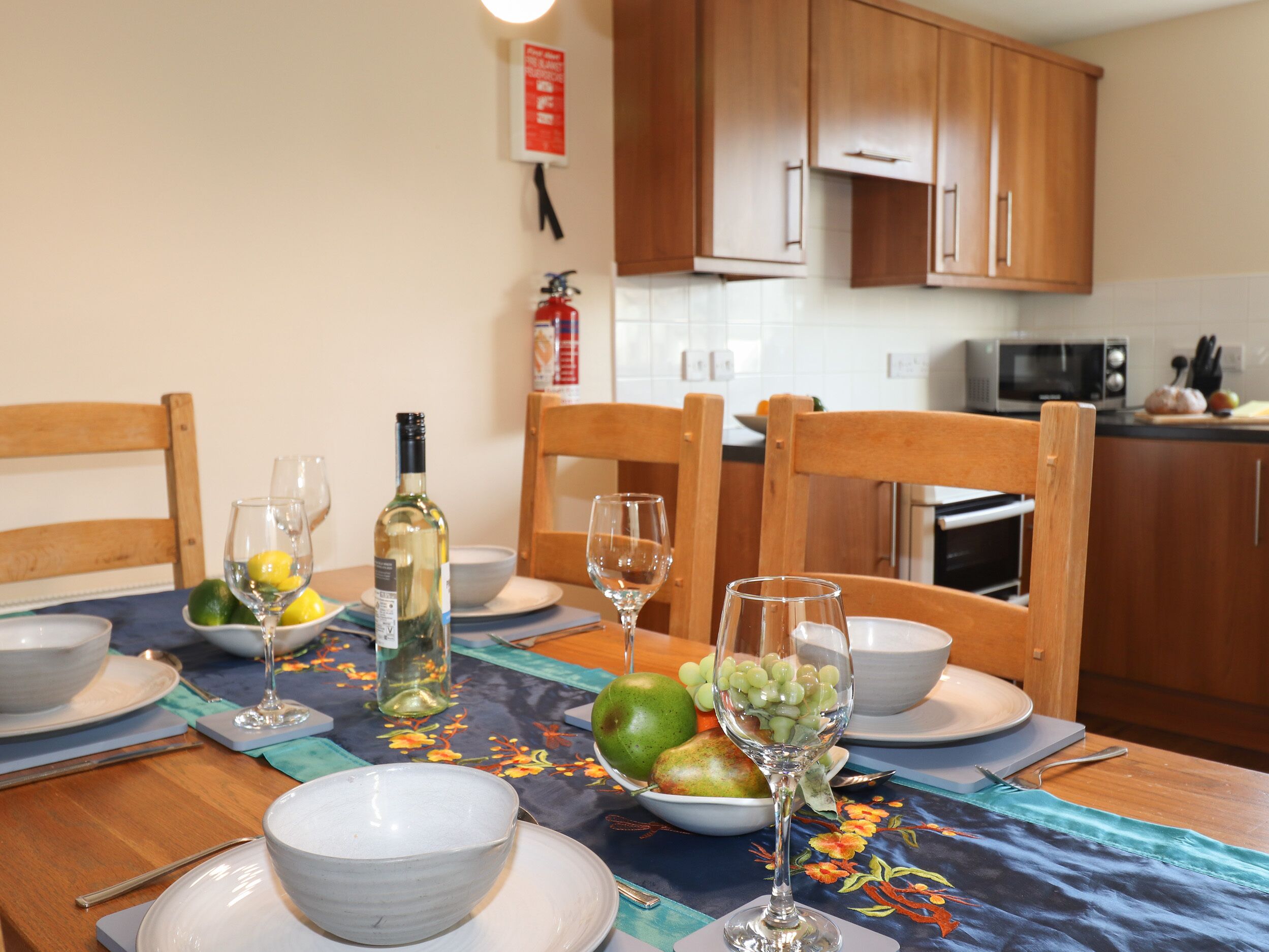 A dining table set with plates, bowls, wine glasses, and a bottle of wine.