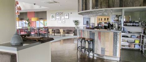 A modern bar area with a curved counter, stools, and a variety of bar tools.