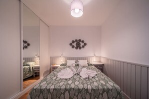 A bedroom with a large bed, two bedside tables, a mirror, and wall decor. - Green Coast (Punta Mujeres)